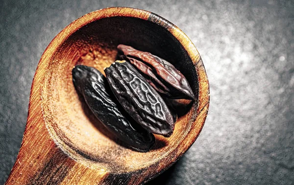 stock image Tonka Beans in a wooden Spoon on a dark background.