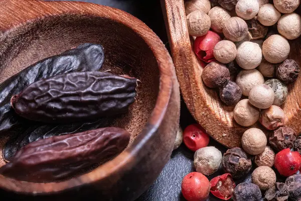 Tonka fasulyesi ve ahşap bir kaşıkta farklı türde karabiber.