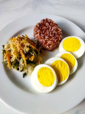 Sebze salatalı kırmızı pirinç ya da gudangan ve beyaz tabakta haşlanmış yumurta. Sağlıklı yemek konsepti.