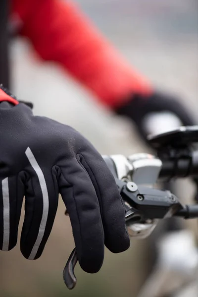 black hand glove detail cyclist handlebars, sleeve red jacket