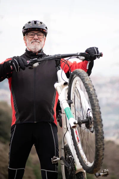portrait of a retired older man dressed as a bicyclist riding his bike