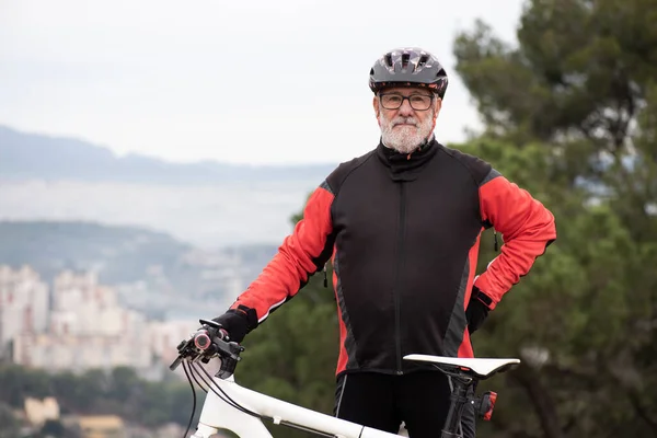 portrait of an older man dressed as a black and red cyclist with his bicycle