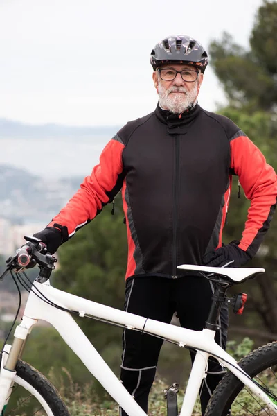 portrait of an older man dressed as a black and red cyclist with his bicycle