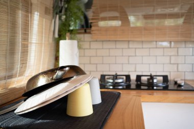 Temiz tabaklar ve karavanın mutfağında kurutma tavası, bambu perdeli pencere minibüsün içinde doğal ve sıcak bir ışık veriyor..