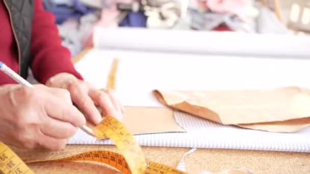 Üzerinde Yaşlı Bir Kadının Çizgili Elbise Kumaşına Çizim Kalıplarının Yapımı — Stok video
