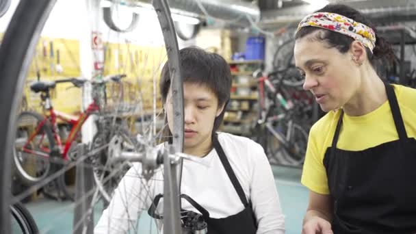 Due Donne Nell Officina Multirazziale Biciclette Comunitarie Una Che Insegna — Video Stock