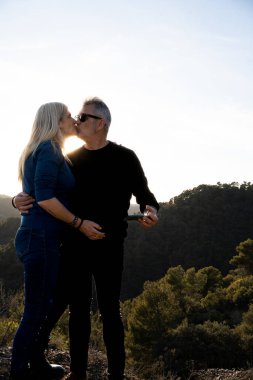 Birbirine aşık çiftler, ikisi de bir tepenin tepesinde siyah giyinmiş, büyük bir dağ manzarası olan, aşık 50 'den fazla insan..