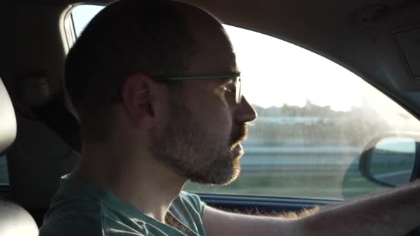 運転中に太陽が目の方向にある日没時の共同運転者からの接触の詳細ビデオ男の運転は彼の目に太陽を得ている — ストック動画