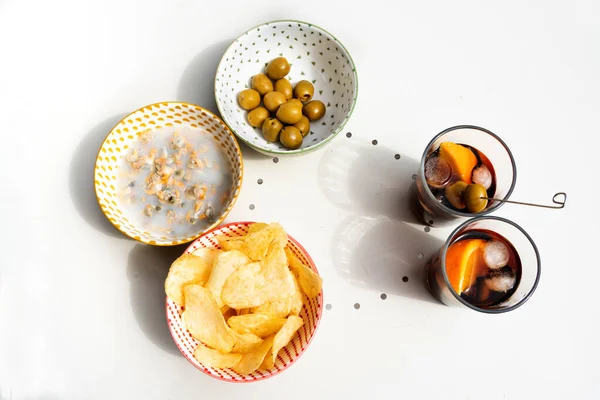 Üç kase abur cubur ve iki bardak vermut, midye, patates ve zeytin dolu balkon masası güneşli bir yaz gününde beyaz masa..