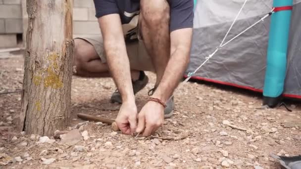 男人在营地上搭帐篷 在坚硬的地面上详细拍摄手和铁锤夹钳的视频 40多岁的高加索人 — 图库视频影像