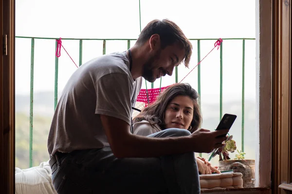 20 'li yaşlarda bir çift kırsal kesimdeki bir otelin balkonundaki cep telefonuna bakıyor, tatil günlerinde dinleniyor.