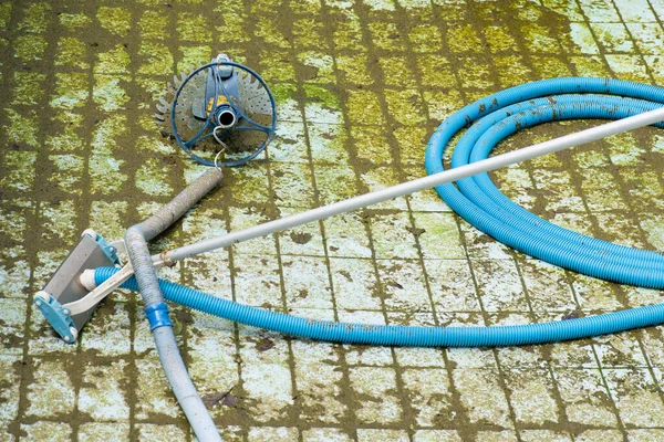detail of pool robot vacuuming dirt from the floor of an empty and dirty pool with algae, blue and green colours, pool without water due to drought and climate crisis