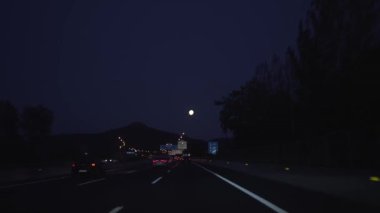 Dolunay ve gece araba sürerken, sokak lambaları ve ışıklarıyla yol videosu..