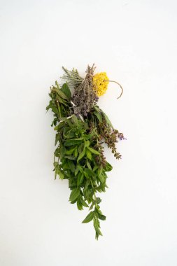 Tıbbi, aromatik bitki filizi olan kekik, nane, ölümsüzlük ya da adaçayının dikey fotoğrafı bir ipin üzerinde kuruyor ve beyaz bir duvara baş aşağı asılıydı..