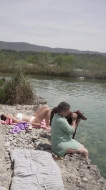 Lezbiyen bir çiftin nehir kıyısında konuştuğu video, 20 'li yaşlarda ayakları suda konuşan iki kadın, uzun esmer saçlı..