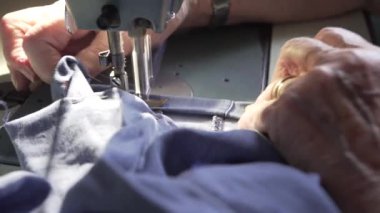 Bir kadının dikiş makinesindeki ellerinin detaylı videosu bir kadının poposunu onarıyor, dikiş deneyimi olan buruşuk elleri var..