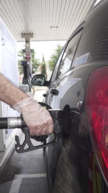 Benzin istasyonunda tanınmayan bir adamın siyah denizaltı vagonuna dizel koyduğu elleri eldivenli ve yaz gezisi için arabayı hazırlarken çekilmiş dikey bir video.