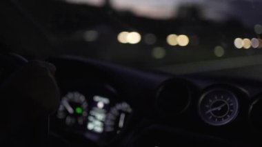 Gece araba kullanırken direksiyondaki elin ayrıntıları kilometre sayacı ve yola odaklanmamış.