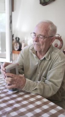 Adam seksenlerinde pilleri değiştirmek için hava durumu istasyonunu söküyor. Yeşil kadife gömlek, gözlük ve gri saç..