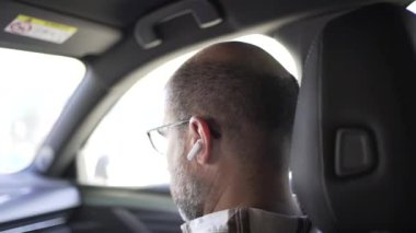 Kablosuz kulaklıklı erkek yardımcı sürücü müzik dinliyor, kulaklıkları çıkardığı hareket.