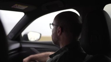 Kel kafalı ve gözlüklü 40 'lı yaşlarda bir adamın yola baktığı yatay bir video..