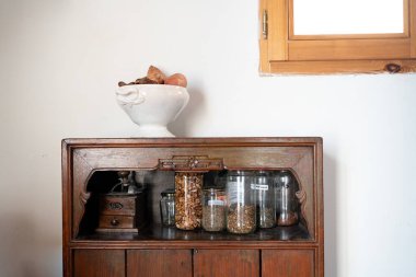 Kestaneli beyaz antika seramik kâse ve beyaz duvarda tatlı patatesler küçük antika ahşap bir dolapta saksılarla