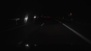 Arabaların ışıkları ve ön camla yağmurda gece araba süren dikey video.