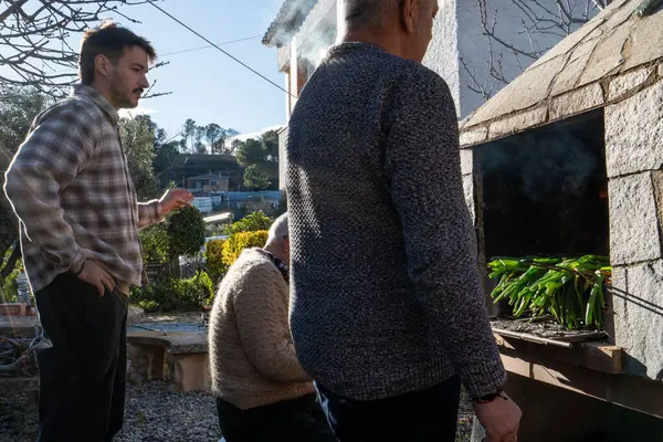 Aile barbeküsü kızartılmış havuç, geleneksel Katalan yemekleri. İnsanlar şöminenin önünde sigara içip konuşuyorlar..