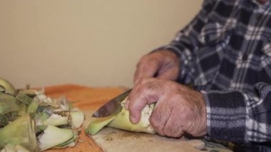 Yaşlı adamın elleri tortilla cipsi, pelüş ekose gömlek kesiyor..