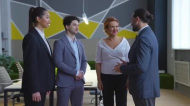 Takım elbiseli erkek ve kadınlar, işçiler, şık bir ofisteki meslektaşlar ellerini bir takım olarak birleştiriyorlar, mutlu, gülerek, projeyi kazanıyorlar..