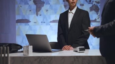 Airport reception, business hall. Close-up of a female administrator, a manager in a uniform is working, typing on a laptop. The man approached the employee and showed his passport