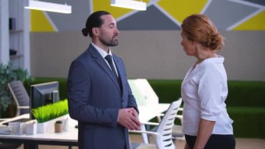 Stylish office man in a suit and woman in a shirt, colleagues, shaking hands, agreeing, smiling