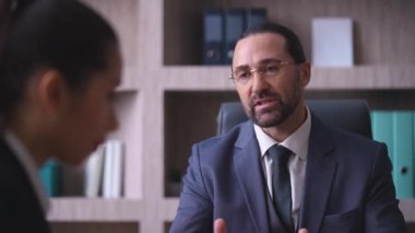 Close-up of male businessman director in glasses in suit and tie in office talking to worker, dissatisfied with work