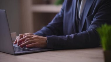 Close-up of male hands typing on a modern laptop, bringing documents, signing with a pen