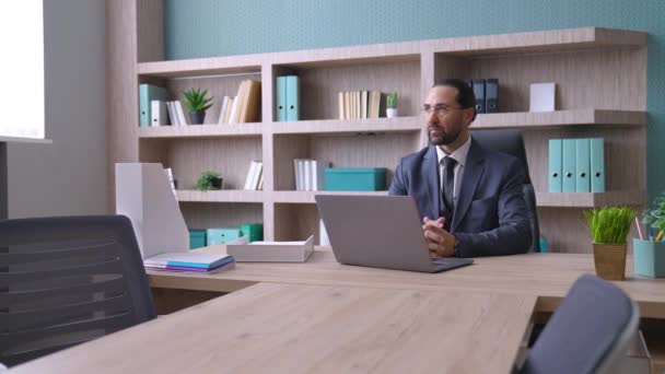 一个穿西装的男人 一个老板 办公室里的眼镜 坐在笔记本电脑前的桌子前 一个工人来了 他们在讨论工作上的问题 一个会议 — 图库视频影像
