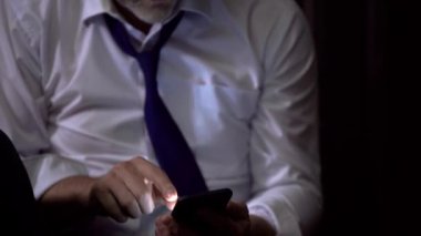 Elinde telefon olan bir adamın yakın çekimi, kamera açılır. İş adamı odada yerde oturuyor, telefonda konuşuyor, kravatını çözüyor, yorgun, üzgün.