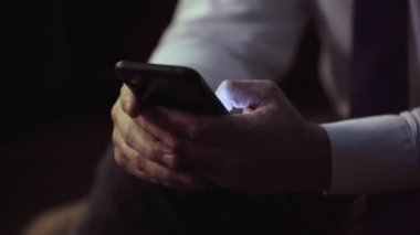 Erkek eli, kravatlı iş adamı, telefonu tutan, mesaj yazan, kaydıran, yakın çekim.