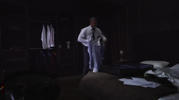 シャツの男とホテルの部屋のパックの服で自宅でビジネスマンネクタイ スーツケースにシャツを投げ イライラし スローモーション ワイドショット — ストック動画
