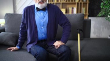 Yaşlı adam, büyükbaba, evinde kanepede oturur, kalbini tutar, göğsünü ovuşturur, iç çeker, derin derin nefes alır.