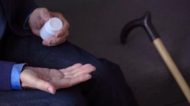 Yaşlı yetişkin bir adam elinde kadın elinin üzerine ağrı kesici haplar tutuyor ilaç alan ilaç şişesinden iki kapsül dolduruyor, yaşlı büyükanne sağlık hizmetleri, eczane ve tedavi konsepti, yakın görüş