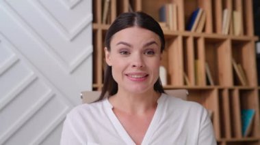 Ofisteki genç bir kadının portresi. Video zoom 'da konuşuyor. Kameraya bakıyor.