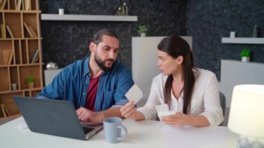 Bir karı koca, dizüstü bilgisayarın önünde bir masada oturur ve faturaları düzenler. Elinde çekler olan genç bir kadın dizüstü bilgisayarında oturan ve evde ciddi şekilde yazan bir genç adam.