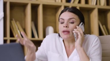 Genç bayan iş kadını telefonda konuşuyor. Duygusal olarak gergin, tartışmaktan rahatsız, yakın plan hareketler yapıyor..