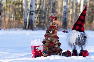 El yapımı cüce ve kırsal dekolteli bir Noel ağacı karda, kırmızı aksanlı..