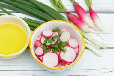 Dilimlenmiş turp salatası (Fransız kahvaltı çeşidi) ve küçük bir kasede yeşil soğan, zeytin yağlı tüm malzemeler beyaz ahşap kırsal masada..