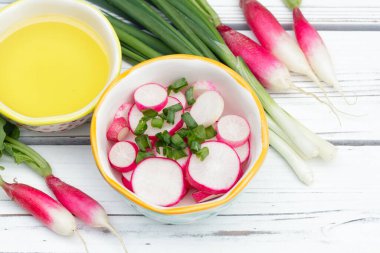 Dilimlenmiş turp salatası (Fransız kahvaltı çeşidi) ve küçük bir kasede yeşil soğan, zeytin yağlı tüm malzemeler beyaz ahşap kırsal masada..