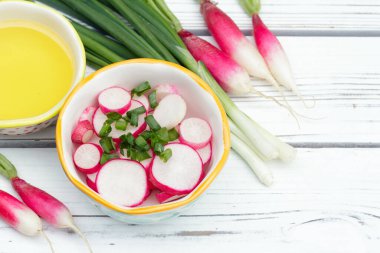 Dilimlenmiş turp salatası (Fransız kahvaltı çeşidi) ve küçük bir kasede yeşil soğan, zeytin yağlı tüm malzemeler beyaz ahşap kırsal masada..