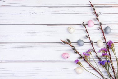 Düz Paskalya kompozisyonu söğüt dalları, kuru çiçekler (gypìila ve statice), beyaz ahşap arka planda tüyler ve yumurtalar ile yatıyordu.