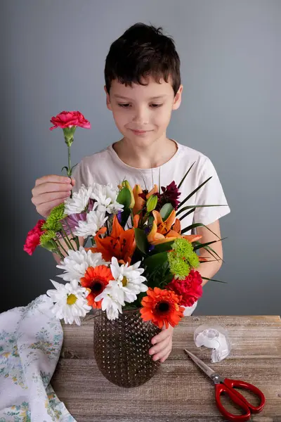 Милый Веселый Мальчик Раскладывает Цветы Букет Вазе Деревянным Столом Дома Лицензионные Стоковые Изображения