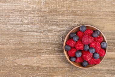 Renkli böğürtlen karışımı - ahududu ve yaban mersini - kırsal kahverengi ahşap bir masada küçük bir ahşap tabakta..